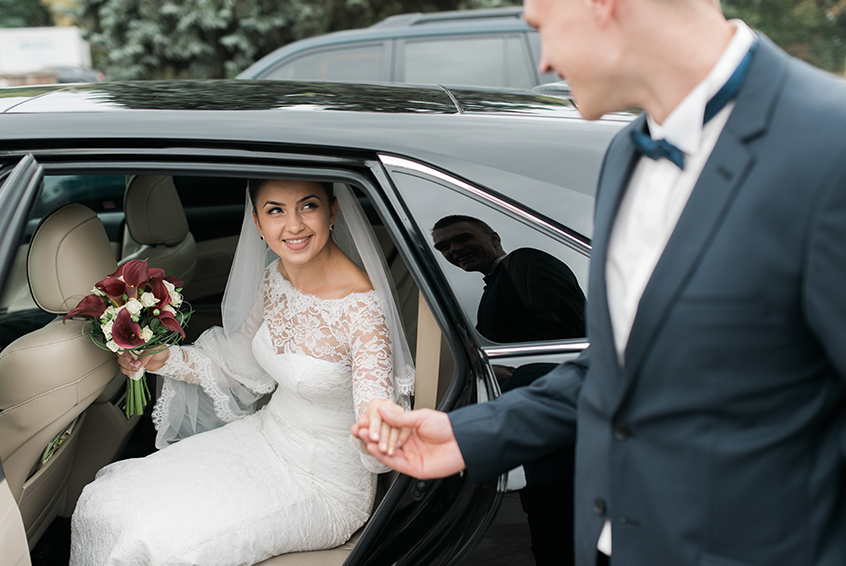 Decorated wedding limousine with bride and groom